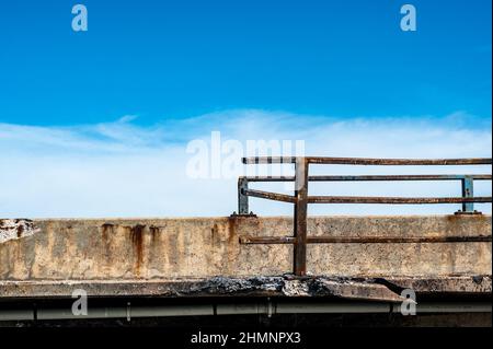 Beschädigte und verbogene Leitplanke entlang der Kante einer Brücke, die repariert werden muss. Stockfoto