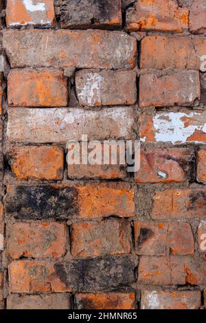 Reparatur einer alten Ziegelwand eines Heizofens. Nach der Reparatur werden verschiedene rote Ziegel in die Wand gelegt. Backstein-Hintergrund Stockfoto