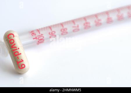 Covid-19 Pillenkapsel und Impfstoff isoliert auf weißem Hintergrund. Neues Behandlungskonzept für neue Covid-19 Varianten Gefahr. Rotes Wort auf weißer Pille. Stockfoto