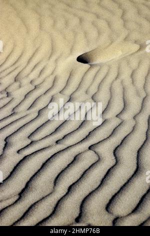Fußabdruck in Sand mit Wellen in Licht und Schatten Stockfoto