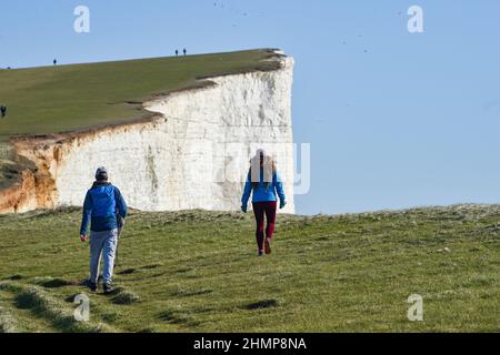 Eastbourne, Großbritannien. 11th Februar 2022 - Spaziergänger genießen einen Spaziergang entlang Beachy Head in der Nähe von Eastbourne an einem schönen sonnigen Nachmittag, aber viel milder und nasses Wetter ist für die nächsten Tage in Großbritannien prognostiziert : Credit Simon Dack / Alamy Live News Stockfoto