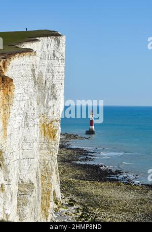 Eastbourne, Großbritannien. 11th. Februar 2022 - Ein Spaziergänger sieht an Beachy Head winzig aus und überblickt den berühmten Leuchtturm in der Nähe von Eastbourne an einem schönen sonnigen Nachmittag, aber viel milderes und nasses Wetter wird für die nächsten Tage in Großbritannien prognostiziert : Credit Simon Dack / Alamy Live News Stockfoto