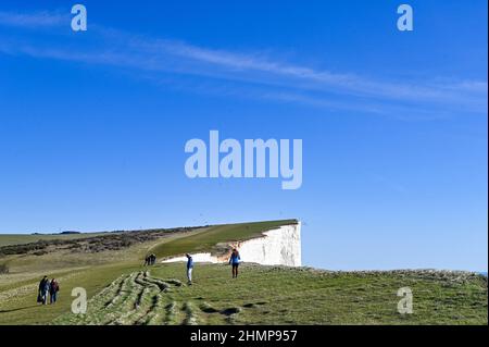 Eastbourne, Großbritannien. 11th Februar 2022 - Spaziergänger genießen einen Spaziergang entlang Beachy Head in der Nähe von Eastbourne an einem schönen sonnigen Nachmittag, aber viel milder und nasses Wetter ist für die nächsten Tage in Großbritannien prognostiziert : Credit Simon Dack / Alamy Live News Stockfoto