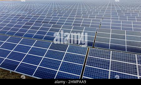 Luftdrohnenflug über Sonnenkollektoren an sonnigen Tagen aus nächster Nähe. Photovoltaik Stockfoto