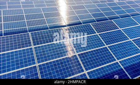 Luftdrohnenflug über Sonnenkollektoren an sonnigen Tagen aus nächster Nähe. Photovoltaik Stockfoto