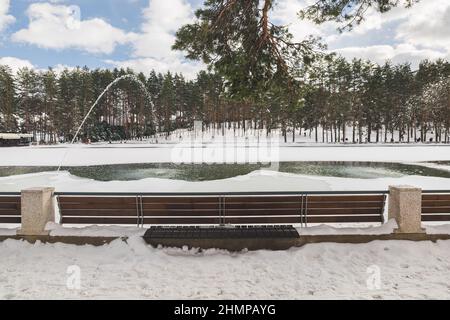 Zlatibor Bergsee im Winter, bedeckt mit Schnee und Eis. Schöner künstlicher See, umgeben von einem schönen Park, Detail mit Bank. Konzentrieren Sie sich auf die Stockfoto