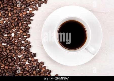tasse schwarzen Kaffee auf einem grauen Holzhintergrund und Geröstete Kaffeebohnen Stockfoto