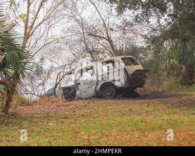 NEW ORLEANS, LA - 8. DEZEMBER 2013: Verlassene, ausgebrannte Autos am Ufer von Bayou St. John mit Nebel und Häusern im Hintergrund Stockfoto