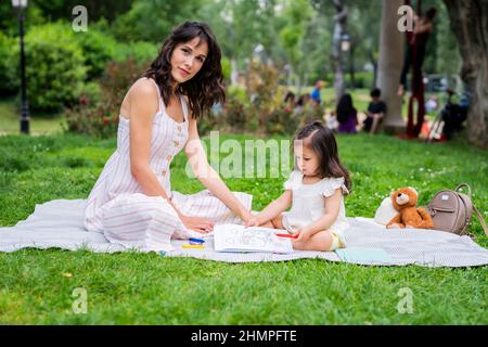 Mutter und Tochter sitzen auf einer Decke im Park Stockfoto