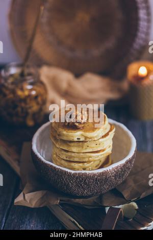 Stapel von leckeren Pfannkuchen mit Honig, Nüsse auf Holzhintergrund Stockfoto