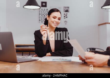 Immobilienmakler stimmen zu, ein Haus zu kaufen und den Kunden in den Büros ihrer Agentur Schlüssel zu geben. Stockfoto