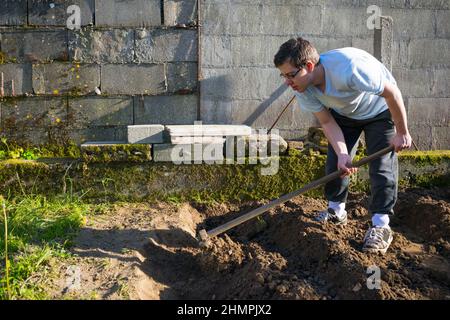 Junger Mann, der in einem Garten Boden gräbt, Spanien Stockfoto