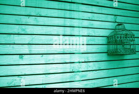 Heller türkisfarbener Grunge-Holzzaun mit einem leeren Vogelkäfig Stockfoto