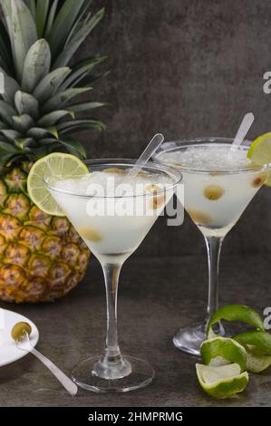 Das Foto zeigt 2 Gläser mit einem alkoholischen Getränk - Tequila. Der Cocktail ist mit einem Limettenkeil dekoriert. Es gibt Oliven im Alkohol. Im Stockfoto