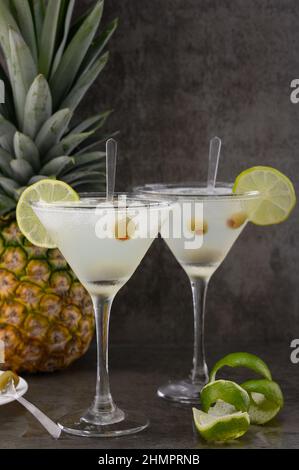 Das Foto zeigt 2 Gläser mit einem alkoholischen Getränk - Tequila. Der Cocktail ist mit einem Limettenkeil dekoriert. Es gibt Oliven im Alkohol. Im Stockfoto