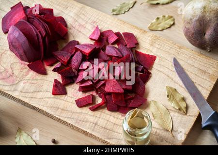 Rote Rüben mit Lorbeerblatt und Piment aufschneiden - Zubereitung von selbst gegärtem Kvass Stockfoto