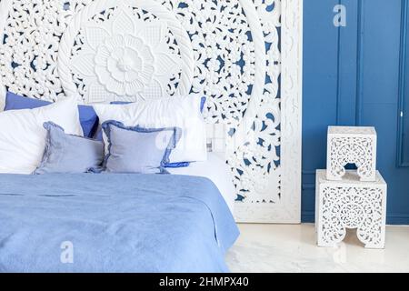 Wunderschönes, klassisches, sauberes, luxuriöses Schlafzimmer in Weiß und Dunkelblau mit Kingsize-Bett und schicken geschnitzten Möbeln. Helles, modernes, stilvolles Schlafzimmer und Wohnzimmer im minimalistischen Stil Stockfoto