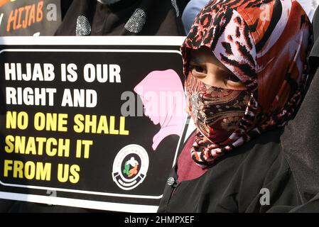 Mumbai, Indien. 11th. Februar 2022. Ein Mädchen mit einem Hijab, das neben einem Plakat auf der Mira Road (Bezirk Thane) zu sehen ist, auf dem steht: „Die Hadjib ist unser Recht und niemand darf sie uns entreißen“. Im College in Karnataka (Bundesstaat Südindien) brach eine Hijab-Reihe über Studenten aus, die an der Hochschule religiöse Kleidung trugen. Der hohe Gerichtshof von Karnataka ordnete an, dass Studenten keine religiösen Kleider an Hochschulen tragen sollten. Die Angelegenheit wird nun am 14th. Februar 2022 gehört. Kredit: SOPA Images Limited/Alamy Live Nachrichten Stockfoto