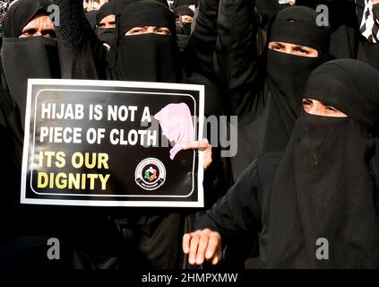 Mumbai, Indien. 11th. Februar 2022. Muslimische Frauen halten während der Demonstration ein Plakat mit der Aufschrift „Hijab ist kein Stück Stoff, seine würde“ an der Mira Road (Bezirk Thane). Im College in Karnataka (Bundesstaat Südindien) brach eine Hijab-Reihe über Studenten aus, die an der Hochschule religiöse Kleidung trugen. Der hohe Gerichtshof von Karnataka ordnete an, dass Studenten keine religiösen Kleider an Hochschulen tragen sollten. Die Angelegenheit wird nun am 14th. Februar 2022 gehört. (Foto von Ashish Vaishnav/SOPA Images/Sipa USA) Quelle: SIPA USA/Alamy Live News Stockfoto