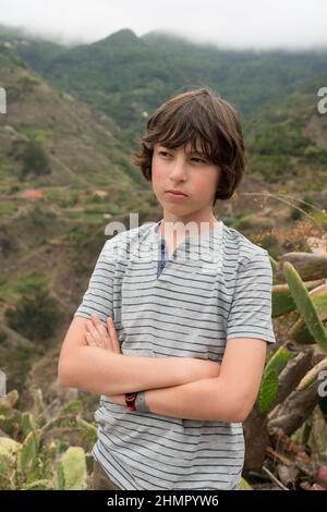 Porträt eines Teenagers in einem Poloshirt auf einem Hintergrund von Bergen. Stockfoto