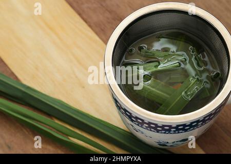 Goiânia, Goias, Brasilien – 11. Februar 2022: Eine Tasse Tee mit Zitronengrasblättern auf einer Holzfläche. Stockfoto