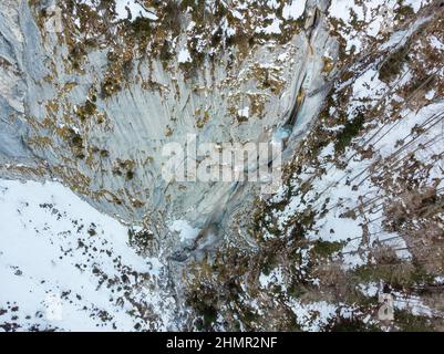 Spektakuläre Luftaufnahme des gefrorenen Wasserfalls, der im Winter über felsigen Felsvorsprung fällt. Stockfoto