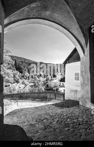 Blick auf die Stadt Rozmberk nad Vltavou durch das Burgtor, Tschechien. Schwarzweiß-Fotografie Stockfoto