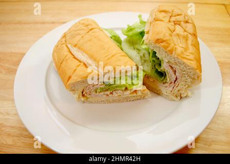 Schinken- und Hühnchen-Deli-Sandwich auf einem weißen Teller Stockfoto