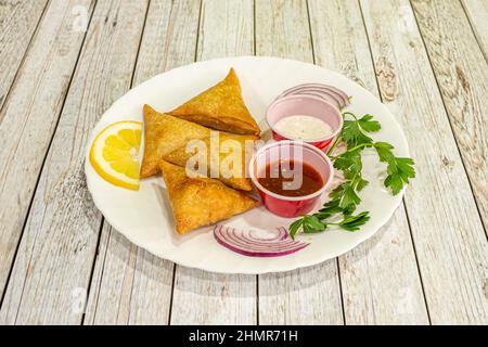 Samosa ist ein gebratener oder gebackener Knödel mit einer herzhaften Füllung, wie gewürzte Kartoffeln, Zwiebeln, Erbsen, Fleisch oder Linsen. Es kann verschiedene Formen annehmen, in Stockfoto