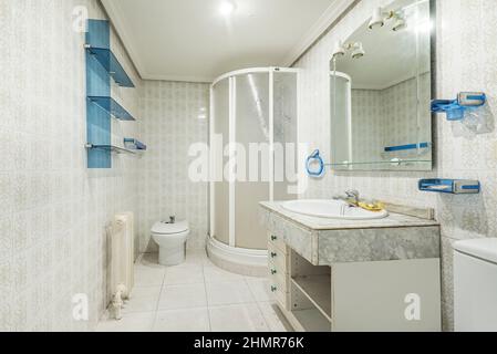 Toilette mit kitschiger Vintage-Dekoration mit blauen Details, viereckiger Duschkabine und Marmorplatte Stockfoto