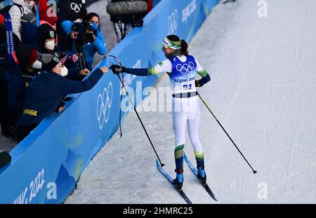 (220212) -- ZHANGJIAKOU, 12. Februar 2022 (Xinhua) -- Jaqueline Mourao aus Brasilien (R) begrüßt mit Teamkollegen und Mitarbeitern im Nationalen Langlaufzentrum in Zhangjiakou, nordchinesische Provinz Hebei, am 10. Februar 2022. Jaqueline Mourao, die 2008 in Peking, wo sie beim Mountainbiken antrat, wieder Fuß setzte, hat als erste brasilianische Athletin seit ihrem olympischen Debüt in Athen 2004 acht Mal Geschichte geschrieben, Und sie ist auch die erste brasilianische Athletin, die sowohl bei Sommer- als auch bei Winterolympiaden antrat."2008 war ich geistig nicht sehr ausgereift", sagte Mourao Stockfoto