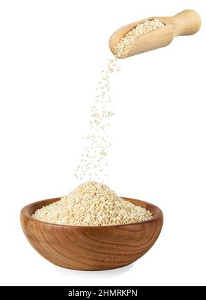 Sesamsamen, die aus der Schaufel in eine Holzschale fallen Stockfoto