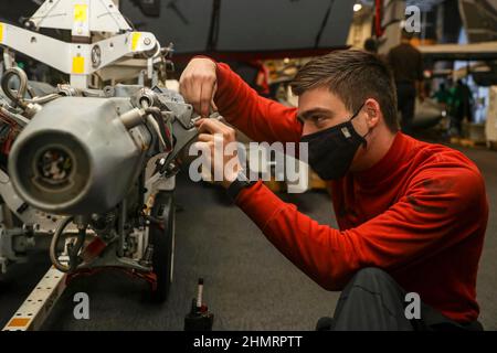 Auf See. 25th Januar 2022. Aviation Ordnanceman 3rd Class Chandler Weitkamp aus Jonesboro, Ark., zugewiesen an die Black Aces of Strike Fighter Squadron (VFA) 41, fixiert eine Halterung an einem verbesserten Multiple Ejector Rack (IMER) in der Hangarbucht des Flugzeugträgers USS Abraham Lincoln (CVN 72) der Nimitz-Klasse. Die Carl Vinson und Abraham Lincoln Carrier Strike Groups führen duale Carrier-Operationen durch, um die Interoperabilität der Joint Force zu verbessern und gleichzeitig unser Engagement für einen freien und offenen Indo-Pazifik-Raum zu demonstrieren. Die US-amerikanische Indo-Pacific Command Joint Force sucht routinemäßig nach Möglichkeiten, in ihr zu operieren Stockfoto