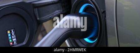 Der elektromobile Ladestecker wird in die Ladebuchse des Fahrzeugs gesteckt Stockfoto