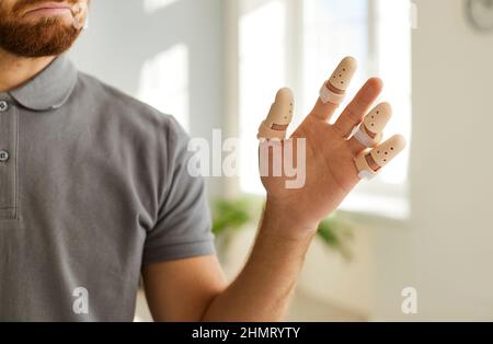 Nahaufnahme der Hand eines Mannes mit verstellbaren Schienen an verletzten oder gebrochenen Fingern. Stockfoto