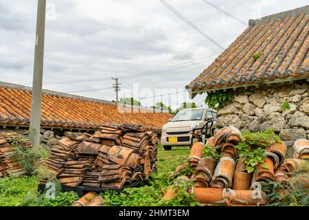 Ein Foto von einem Ziegelstein, einem Auto und einem Haus, das an einem bewölkten Tag in der ländlichen Stadt Okinawa, Japan, aufgenommen wurde Stockfoto