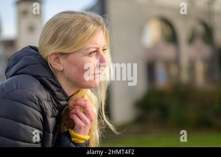 Profil von headshot eine hübsche junge blonde Frau mit einem glücklichen Lächeln in einem städtischen Umfeld Stockfoto