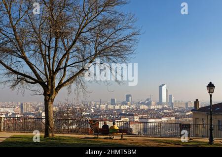 LYON, FRANKREICH, 25. Januar 2022 : Ein Paar auf einer Bank bewundert den Blick auf das Stadtzentrum von Lyon von den Hängen des Croix-Rousse-Hügels Stockfoto