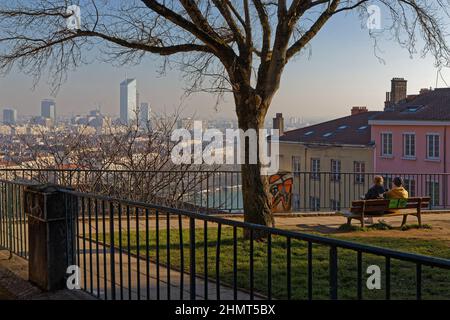 LYON, FRANKREICH, 25. Januar 2022 : Ein Paar auf einer Bank bewundert den Blick auf das Stadtzentrum von Lyon von den Hängen des Croix-Rousse-Hügels Stockfoto