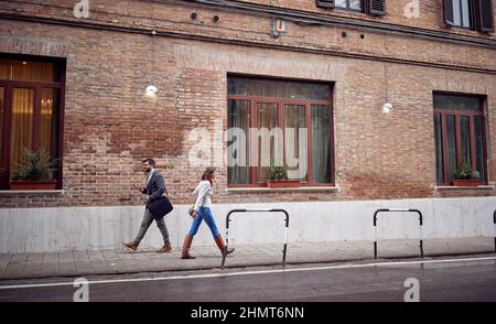 Fußgänger, die an einem bewölkten Tag eilig auf dem Bürgersteig in der Stadt aneinander vorbeikommen. Zu Fuß, Stadt, Straße Stockfoto