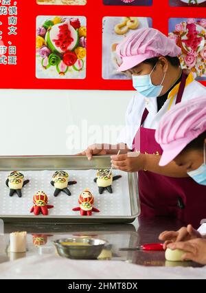 ZOUPING, CHINA - 12. FEBRUAR 2022 - Ein Konditor stellt in Z Dampfbrötchen in Form von Bing Dwen Dwen, dem Maskottchen der Olympischen Winterspiele in Peking, her Stockfoto