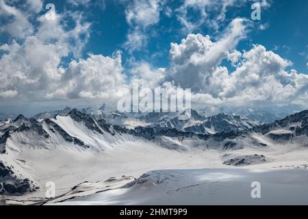 Bergwolken über wunderschönen schneebedeckten Gipfeln von Bergen und Gletschern. Blick auf die verschneiten Berge. Stockfoto