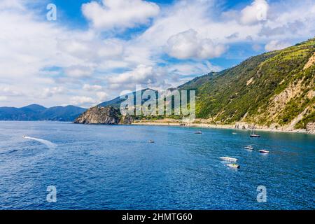 CINQUE TERRE, ITALIEN - 18. Juli 2019: Klassischer Blick auf Manarola - Bunte Häuser in einer dramatischen Felsformation am Meer mit einem natürlichen Fischfang Stockfoto