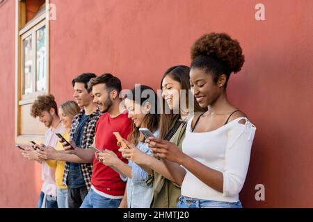 Junge, multirassische Gruppe von Freunden, die ihr Smartphone im Freien nutzen – Generation der Millennials, die Spaß mit neuen Trends bei Social-Media-Apps hat Stockfoto