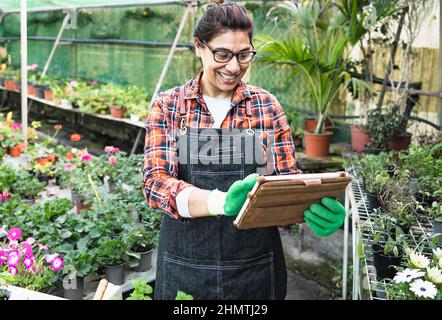 Hispanische Frau, die im Blumengartengeschäft mit einem digitalen Tablet arbeitet Stockfoto