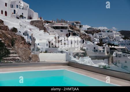 Wunderschöner randloser Pool mit Blick auf Santorini, Oia-Stadt, Griechenland. Weiße Architektur auf der Insel Santorini. Sommerurlaub und Urlaubskonzept, Luxus Stockfoto