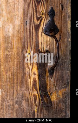 Altes Blockhaus. Türen, Tore. Geschmiedete Türgriffe aus rostetem Metall, Schrauben, Scharniere, Haken. Schäbiger Baum, gealterte Holzstruktur. Stockfoto