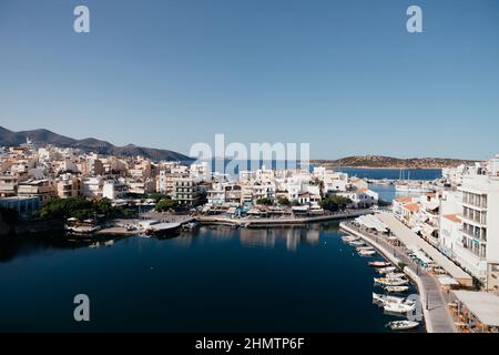 Schöne Aussicht auf die kleine Stadt Agios Nikolaos und den Voulismeni-See auf Kreta, Griechenland. Ort mit geschäftigen touristischen Leben am Wasser mit Café und Stockfoto