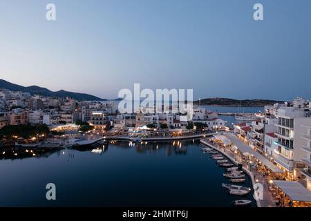 Schöne Aussicht auf die kleine Stadt Agios Nikolaos und den Voulismeni-See auf Kreta, Griechenland. Ort mit geschäftigen touristischen Leben am Wasser mit Café und Stockfoto