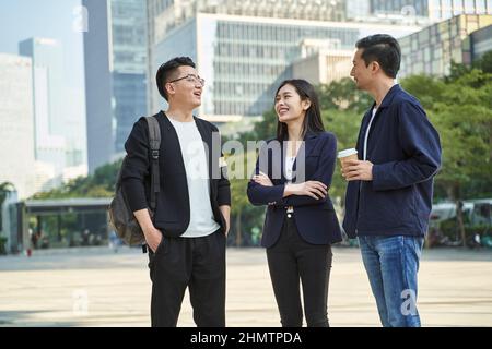 Junge asiatische Menschen stehen auf der Straße und sprechen glücklich und lächelnd Stockfoto
